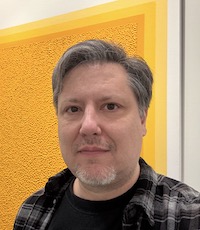 image of the artist standing in front of artwork on display